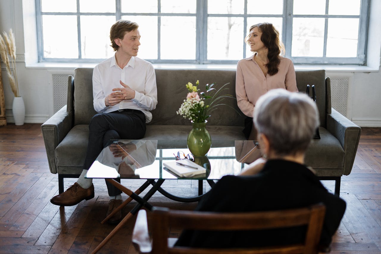 who-we-are Couple engaged in a therapy session with a counselor in a loft setting.