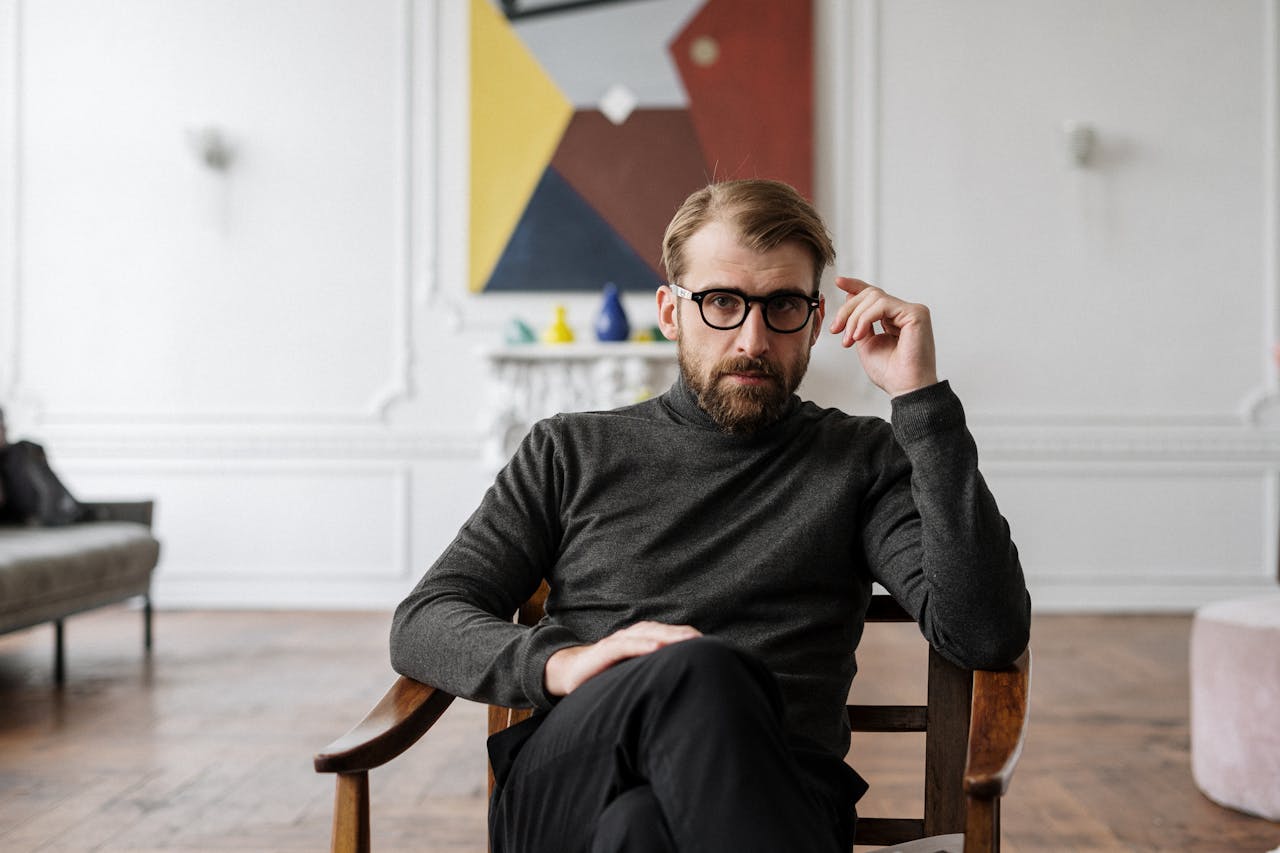 team-01 Man with glasses seated in modern interior with abstract art.